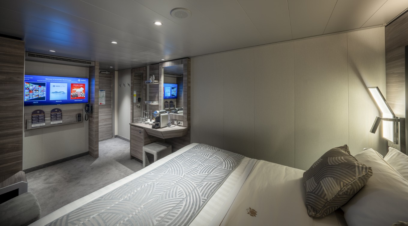 An interior stateroom on MSC Europa, featuring a room with a bed and a mirror, a mattress, pillows, and a grey floor with white lines, with no faces or objects detected.